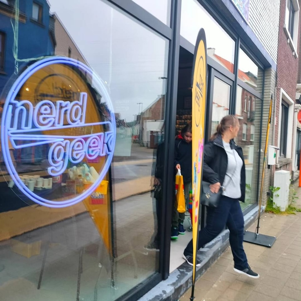 nerdgeek Erembodegem retail store front with logo, flag and windows nerdgeek Erembodegem retail store front with logo, flag and windows